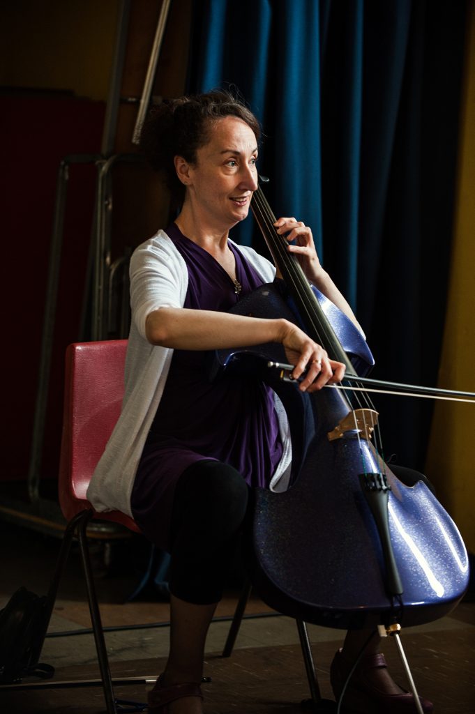 Jo-anne sits proud, drawing a bow across the strings of her electric cello, an expectant, listening expression on her face